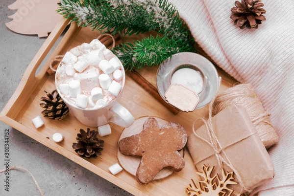 Fototapeta hot chocolate with marshmallows and cinnamon, spruce branch, cookies, cones, gingerbread man, candle, snowflakes, gift, box, top view