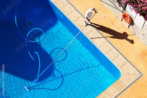 Obraz utility worker cleaning the swimming pool with vacuum equipment	