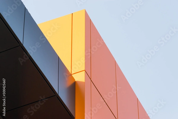 Fototapeta Geometric color elements of the building facade with planes, lines, corners with highlights and reflections for an abstract background and texture of gray, orange colors. Place for text