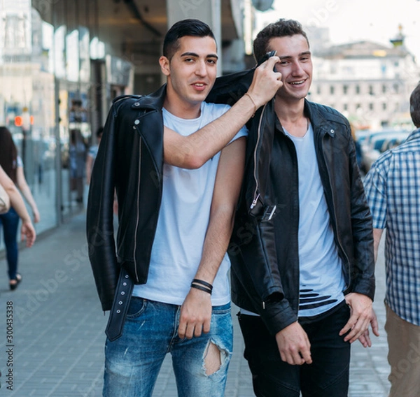Obraz beautiful and attractive guy is standing in the city, posing. walk around the city in black glasses. communication. meeting friends.