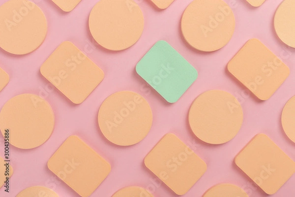 Fototapeta A lot of sponge, a beautiful blender for applying foundation or powder. Flat lay on a pink background, copy space.