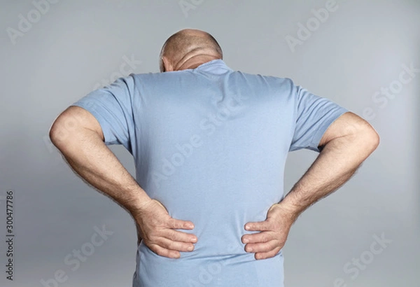 Fototapeta Mature man suffering from backache on light grey background