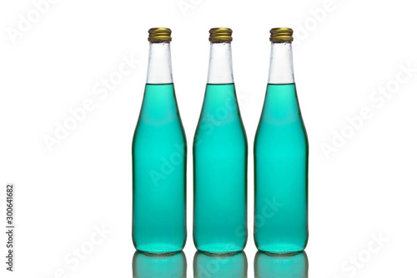 Fototapeta Three large glass bottles with light blue liquid stand on a mirror surface on a white background in the middle.