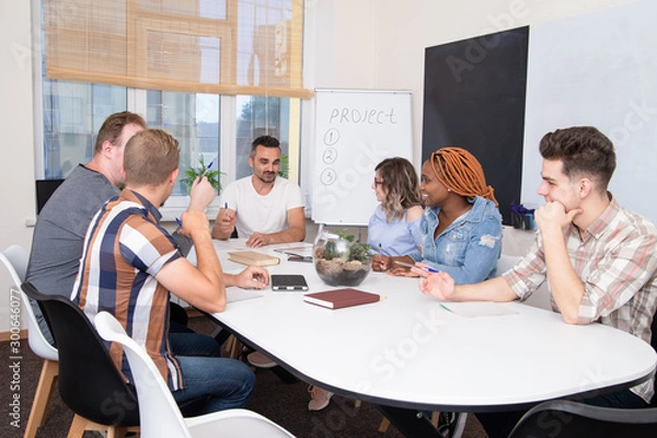 Obraz A group of people at a business training listens to the speaker or chief. Teamwork in an international company, students