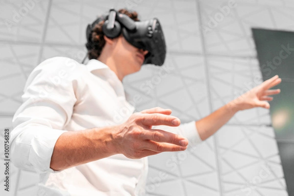 Obraz Young excited Man wearing virtual reality goggles in modern bright co-working office. the VR experience.
