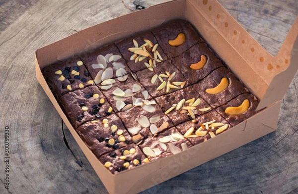 Fototapeta Fudge brownies in a brown paper box on wooden table