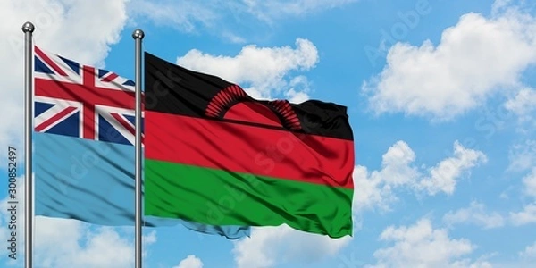 Fototapeta Fiji and Malawi flag waving in the wind against white cloudy blue sky together. Diplomacy concept, international relations.