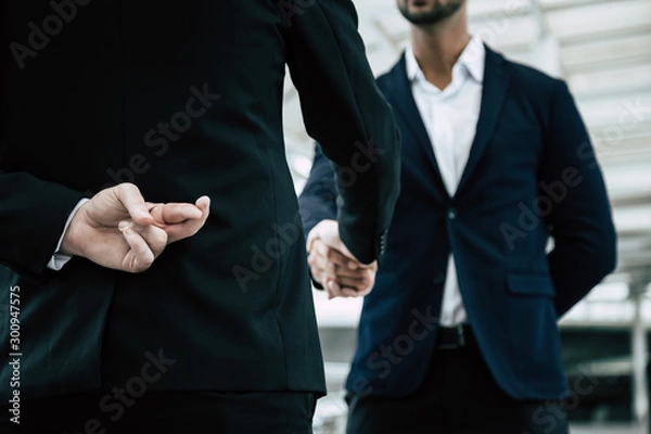 Fototapeta Businessman or politician cross finger, hiding behind his back during he get handshake to another person, businessman. Businessman pretend to be good person, he is liar. White collar worker is fraud