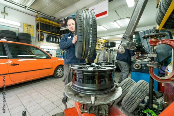 Fototapeta Auto mechanic working in mechanical workshop. Tire replacement.