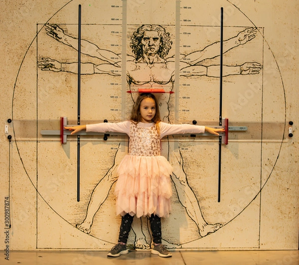 Fototapeta Little girl on the background of the Vitruvian man. The concept of body proportions