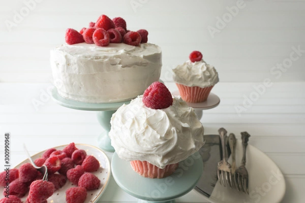 Fototapeta Raspberry cupcakes and whole cake decorated with fresh raspberries and vanilla frosting. 