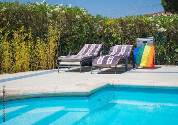 Fototapeta gay pride flag waving between two sunbeds before a party