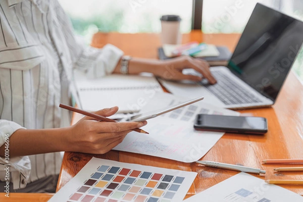 Fototapeta Creative startup freelance graphic designer concentrating on computer screen for designing , coding, programing mobile application from prototype and wireframe layout.