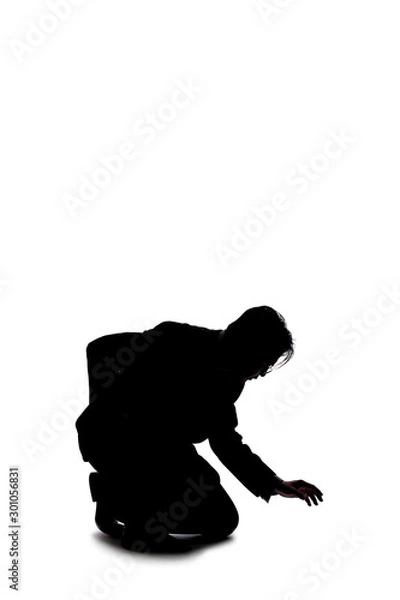 Fototapeta Silhouette of a backlit model posing as a businessman on a white background.  He is crouched on the ground like a detective looking or searching for something on the floor