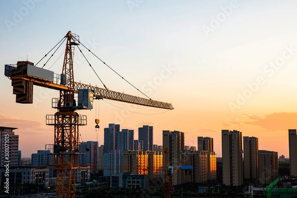 Fototapeta Tower cranes build residential buildings at nigh