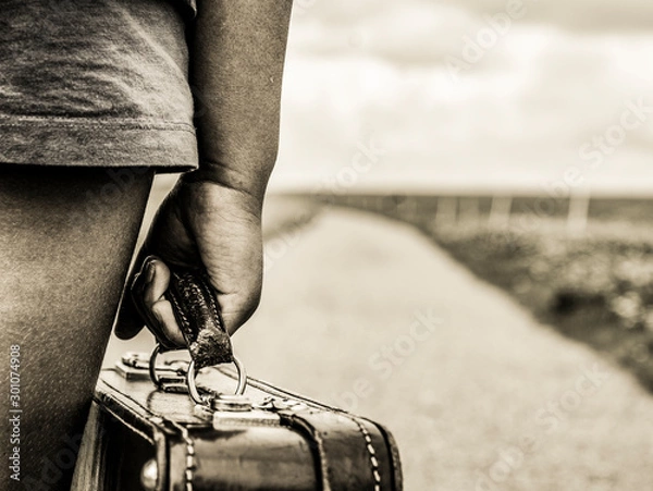 Fototapeta Immigrant child fleeing with her suitcase across the border