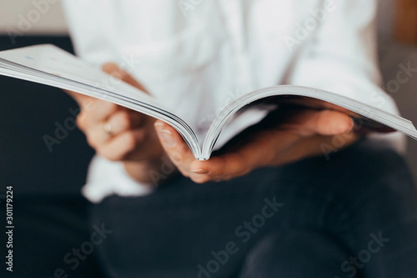 Obraz Beautiful female hands hold an open book or magazine in the room