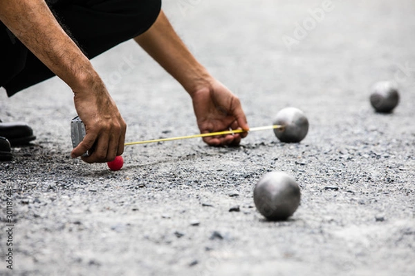 Fototapeta Man measuring the distance of petanque ball in petanque field