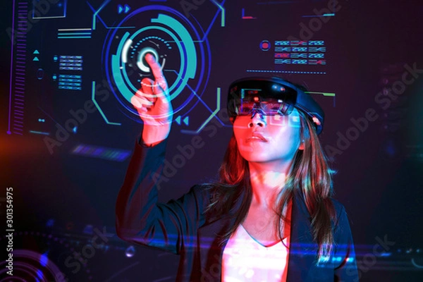 Fototapeta Young asian girl try augmented and virtural reality glasses hololens in the lab room. Mixed reality future technology concept.