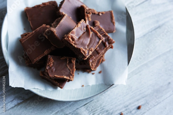 Obraz Czekoladowe krówki kwadraty na pergaminie i tle drewna z miejsca na kopię.