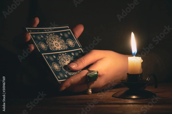Fototapeta Fortune teller reading a future by tarot cards in the light of candle concept.