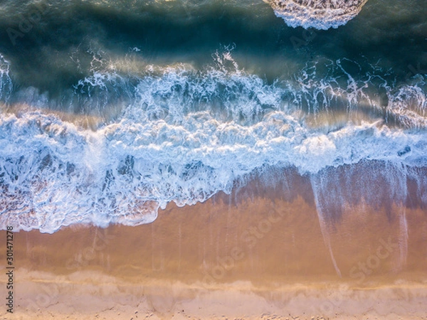 Fototapeta Drone picture of waves hitting the beach.