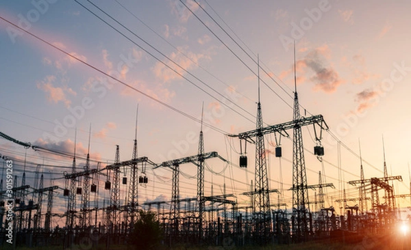 Fototapeta The silhouette of the evening electricity transmission pylon. Power transmission from a power plant to a city.