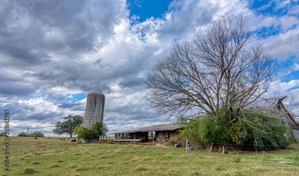 Obraz Abandoned barn with silo under stormy clouds