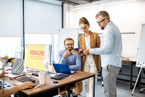 Fototapeta Group of diverse creative people having a small discussion, working as a web designers in the modern office or coworking space