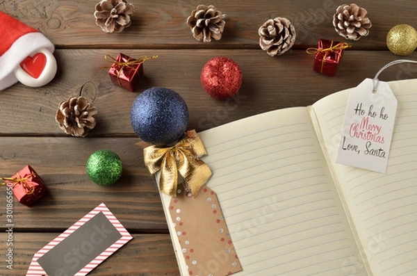 Fototapeta Christmas decorations, star and balls on wooden table. Notebook for new year greetings. Festive decoration, on a brown wooden table with space for text.