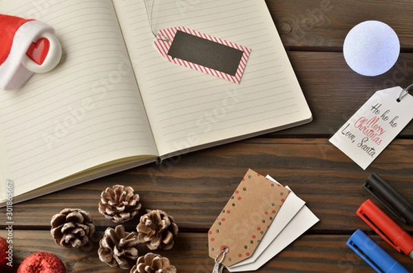 Fototapeta Christmas decorations, star and balls on wooden table. Notebook for new year greetings. Festive decoration, on a brown wooden table with space for text.