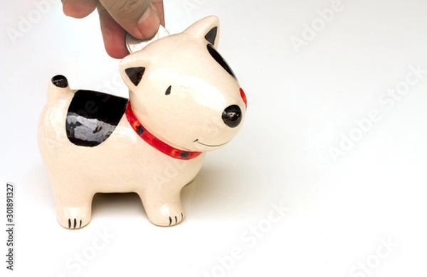 Obraz Saving, male hand putting a coin into piggy bank.