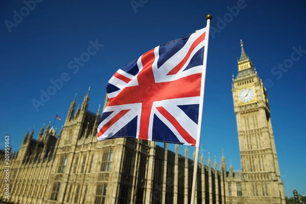 Fototapeta Single Union Jack flag waving in front of Big Ben at the Houses of Parliament in London, UK on a clear sunny day