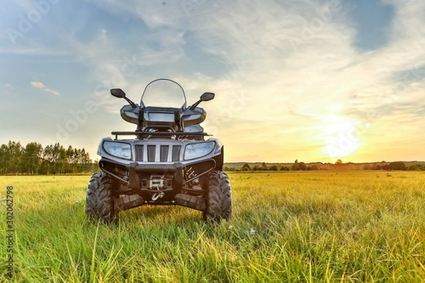 Fototapeta gray ATV on grass in summer at sunset with copy space. beautiful quad bike at sunset in summer front side view