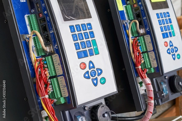 Obraz Controllers for remote control with buttons for direct control and settings are arranged in a row. Electrical wires and network cable are connected to the controllers. Devices have a screen.