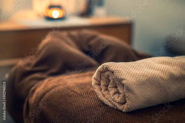 Obraz Stół do masażu z ręcznikiem i świecą w pokoju, spa