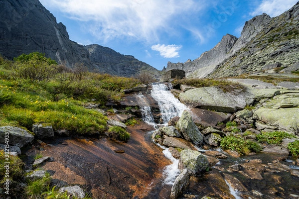 Fototapeta River flowing through autumn colorful forest. Beautiful fall river with rocks and trees
