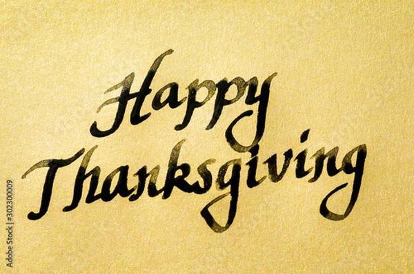 Fototapeta Happy Thanksgiving message handwritten in black calligraphy script on textured gold paper