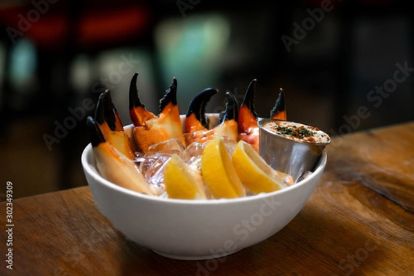 Fototapeta Fresh Stone Crab Claws with lemon and lime, sauce and ice in a dish in a restaurant