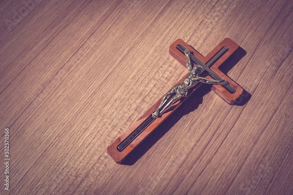 Fototapeta Scene of the wooden cross with metal Jesus Christ with light and shadow and bible on wooden floor, good friday, easter, with blank copy space