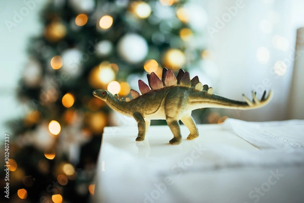 Fototapeta green dinosaur with spikes on the background of a Christmas tree