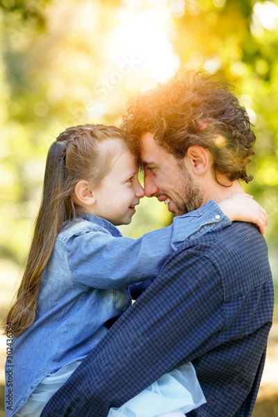 Obraz Family life. Portrait of dad and daughter in the Park. They pressed their foreheads together.