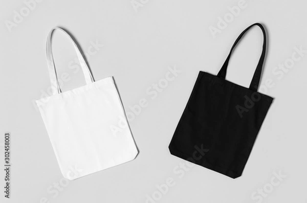 Fototapeta White and black tote bags mockup on a grey background.