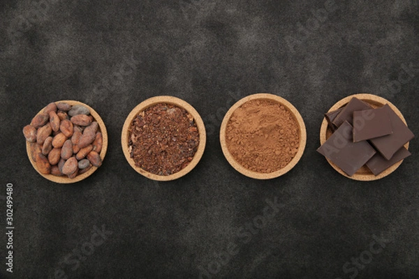 Fototapeta organic cacao beans, cocoa powder, ground and chocolate on a black background with copy space for text. Flat lay, top view. Ingredient. Vegan food. Background, pattern, card, menu. 