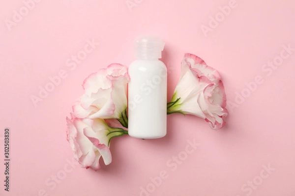Fototapeta Beautiful flowers and blank bottle on pink background, space for text