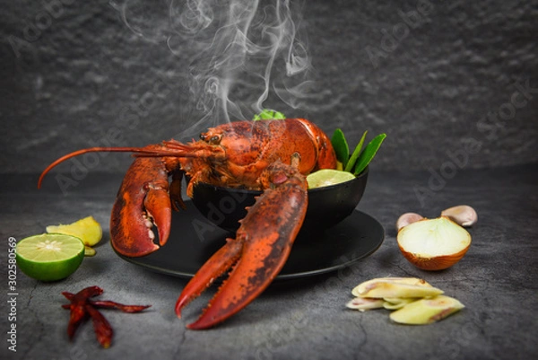 Obraz Red lobster spicy soup bowl - Cooked seafood with lobster dinner table and spices ingredients on black plate thai food