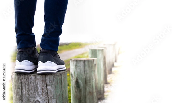 Fototapeta A woman standing on stump next to the road. Concept of living life with confidence and carefulness every steps of moving forward to make sure life safe. Free copyspace for text on right.
