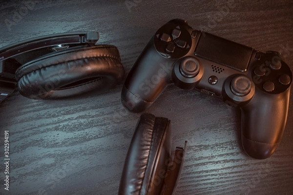 Obraz Gaming headphones and wireless controller, on a wooden table