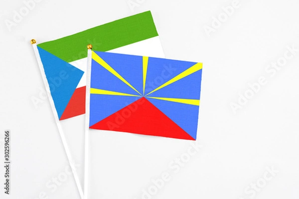 Fototapeta Reunion and Equatorial Guinea stick flags on white background. High quality fabric, miniature national flag. Peaceful global concept.White floor for copy space.