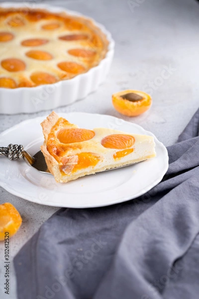 Fototapeta Apricot and cottage cheese pie or shortbread crust cake in white baking pan on dark grey washed linen table cloth, summer fruit dessert 